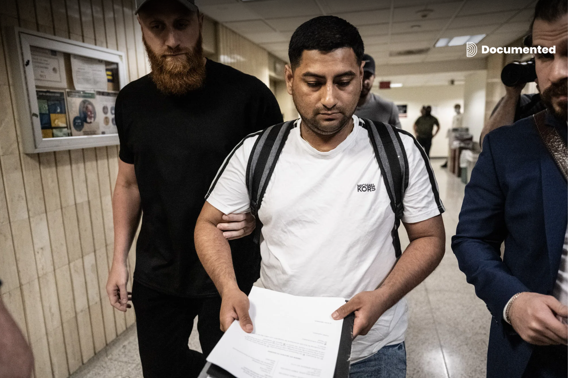 Agentes de ICE en los pasillos del 26 Federal Plaza detienen a un inmigrante el 6 de junio de 2025 en la ciudad de Nueva York. En su mano lleva los documentos de la corte.
