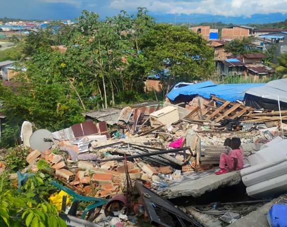 Un niño del barrio La Carmelita (Buenaventura) está sentado sobre los escombros de una casa vecina.