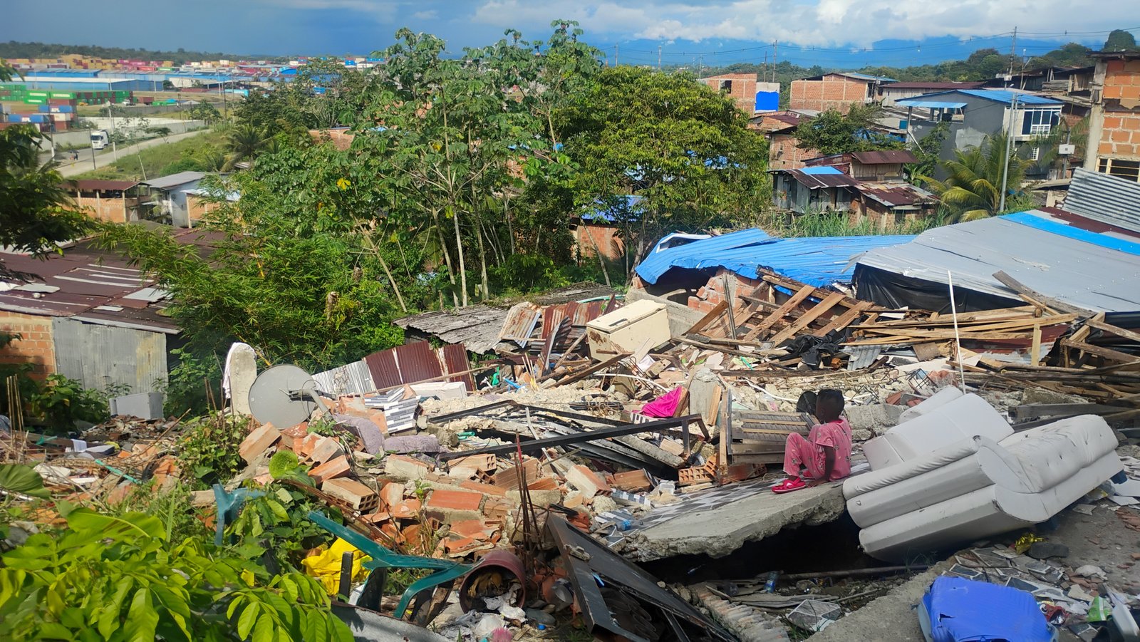 Un niño del barrio La Carmelita (Buenaventura) está sentado sobre los escombros de una casa vecina.