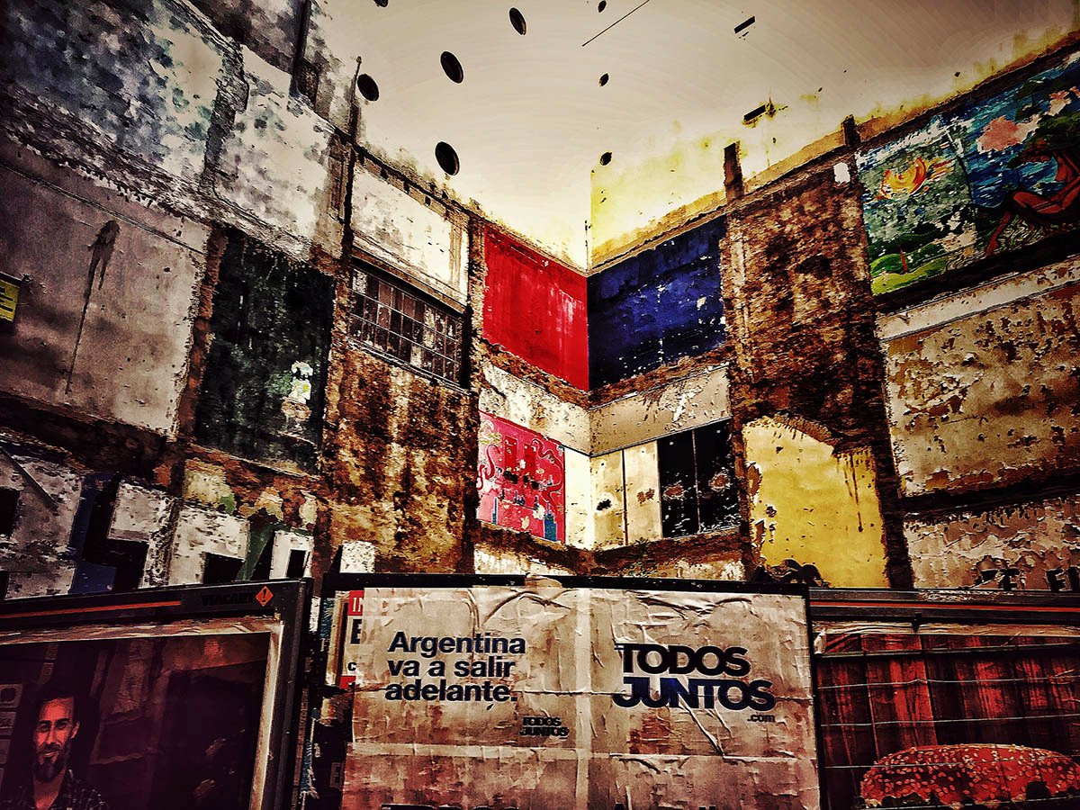 Paredes interiores deterioradas con capas de pintura de colores y carteles con las frases «Argentina va a salir adelante» y «Todos juntos».