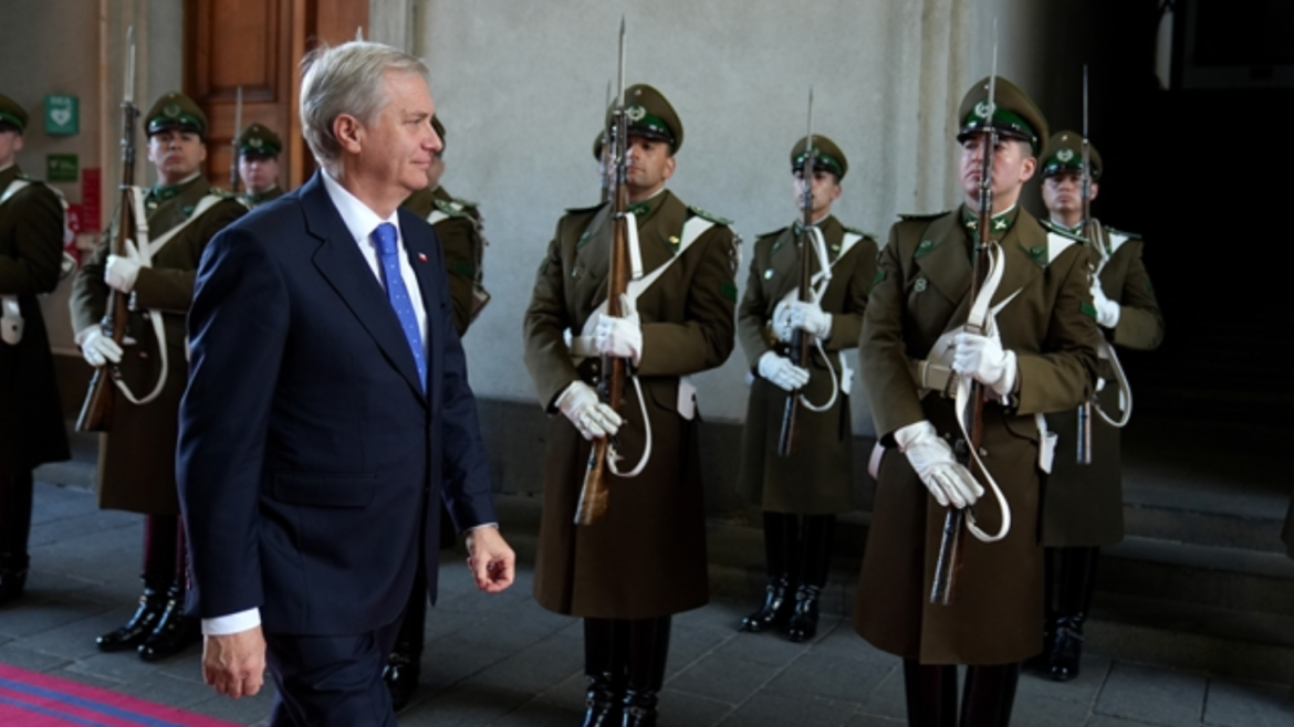 José Antonio Kast, de traje azul oscuro y corbata azul, camina por una alfombra roja frente a una guardia de honor de Carabineros en La Moneda.