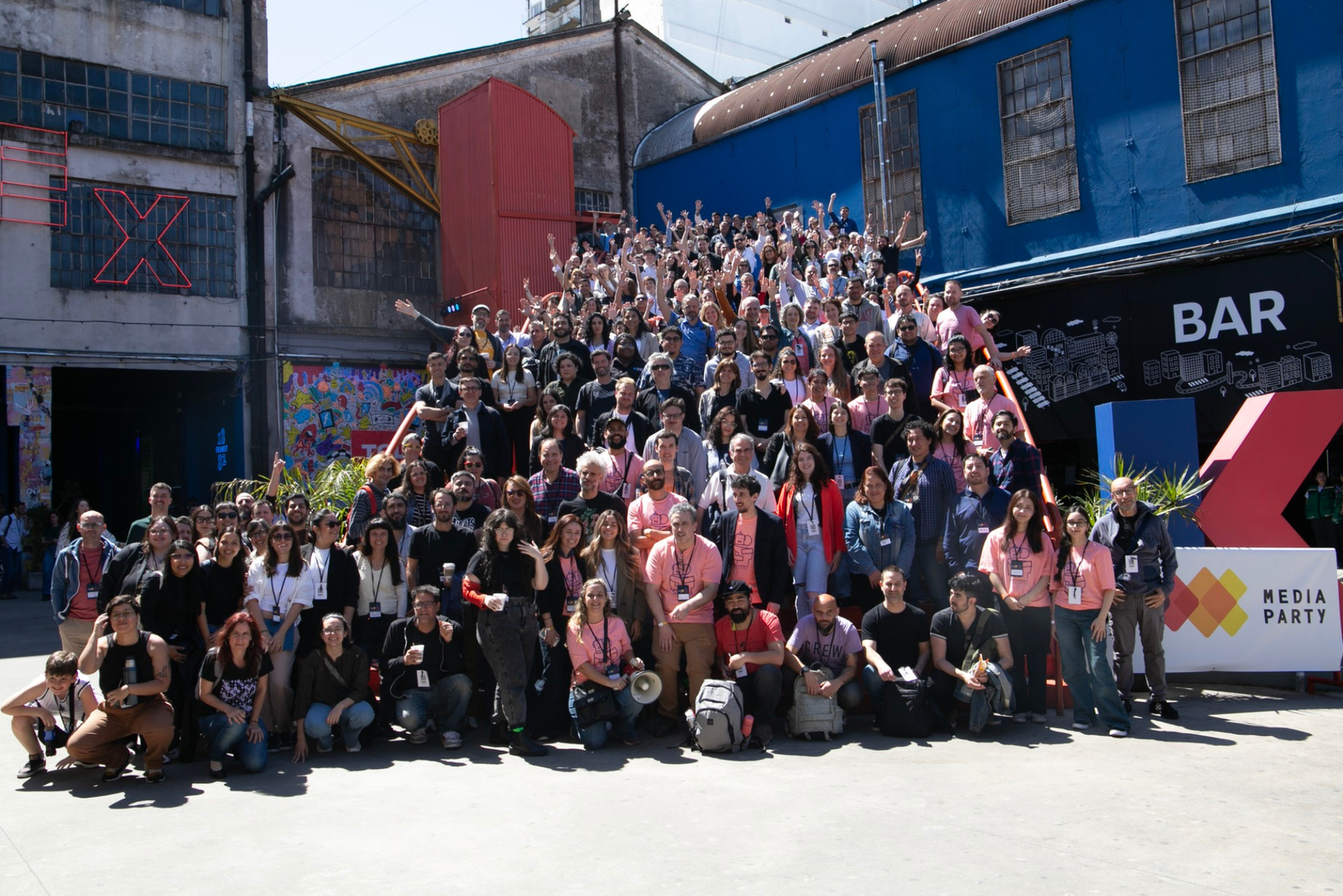 Foto grupal de cientos de participantes de Media Party en las escaleras de la Ciudad Cultural Konex, muchos con los brazos en alto